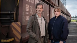 Eine Frau und ein Mann stehen vor einem ausrangierten Zug