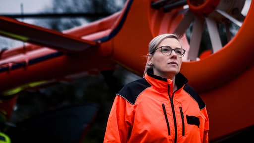 Eine Frau, Teil der Christoph 9-Crew, steht vor einem Hubschrauber.