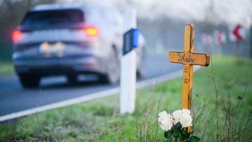 Ein Kreuz zum Gedenken an ein Opfer eines Verkehrsunfalls steht an einer Landstraße.
