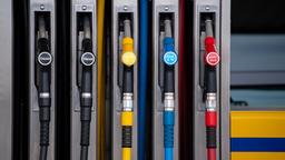 Zapfpistolen für verschiedene Kraftstoffarten hängen an einer Zapfsäule an einer Tankstelle.